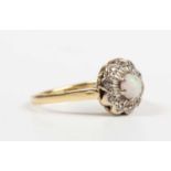 A gold, opal and diamond cluster ring, claw set with the circular opal within a diamond set