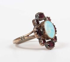 A gold, opal and garnet oval cluster ring, mounted with an oval opal within a garnet set surround,