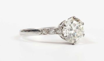 A platinum and diamond ring, claw set with the principal circular cut diamond between diamond