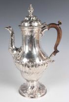 A George III silver baluster coffee pot with domed hinged lid and seed head finial above half-spiral