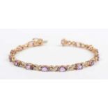 A gold, amethyst and diamond bracelet, claw set with a row of oval cut amethysts alternating with