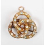 A gold, diamond and enamelled pendant brooch in an entwined trefoil design, claw set with a