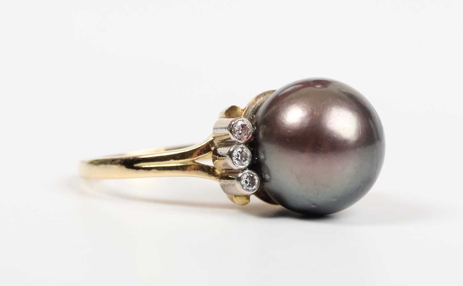 An 18ct gold ring, mounted with a large grey tinted cultured pearl between two rows of three