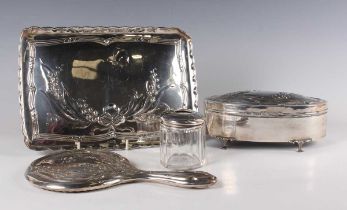 A George V matched silver four-piece dressing table set, each piece embossed with lily-of-the-