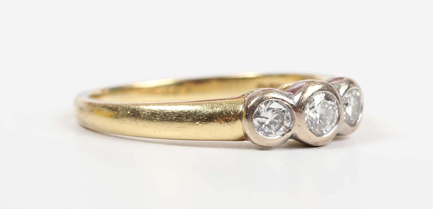 An 18ct gold and diamond three stone ring, collet set with a row of circular cut diamonds, Sheffield