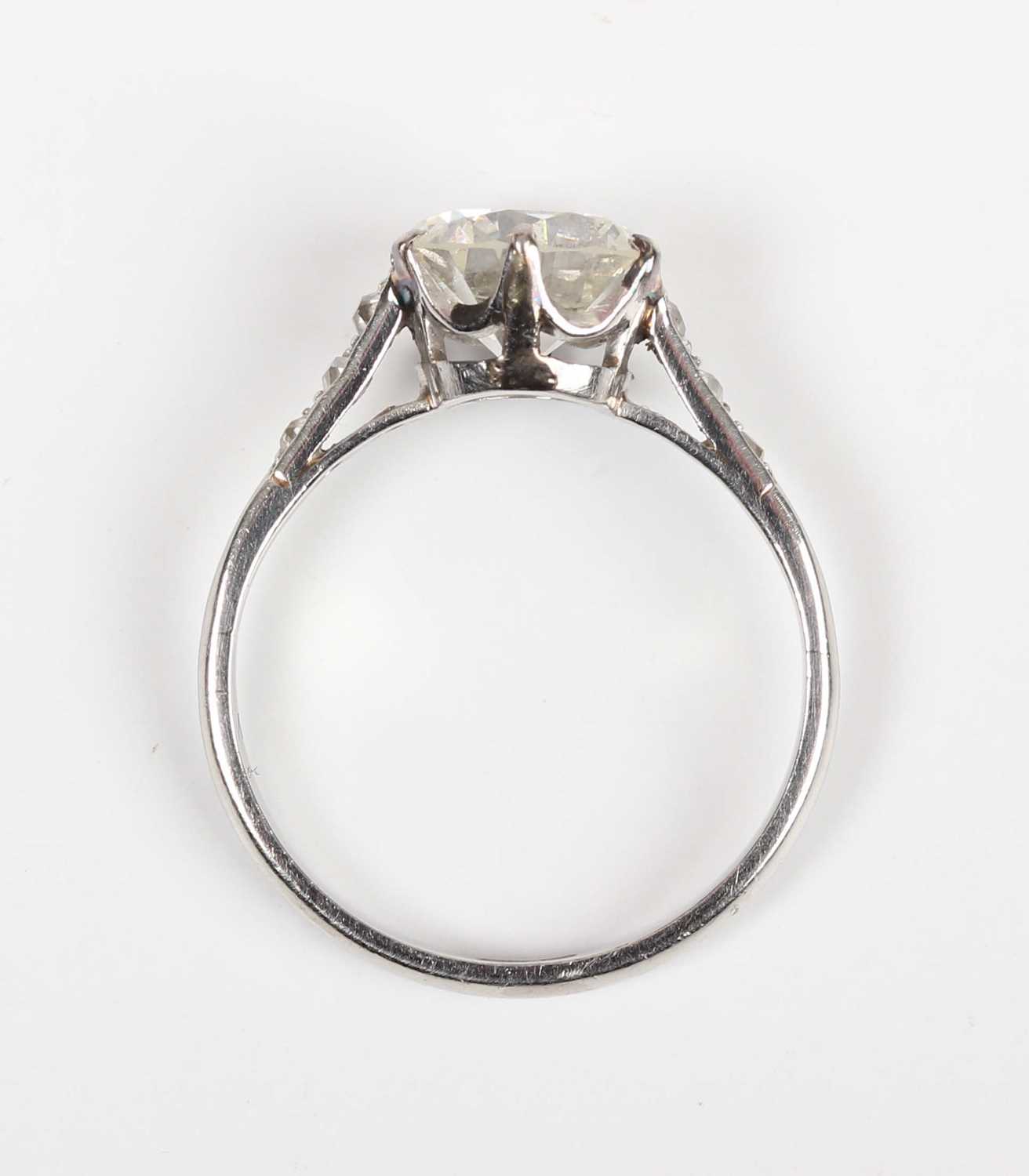 A platinum and diamond ring, claw set with the principal circular cut diamond between diamond - Image 4 of 5