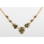 A gold and green sapphire necklace, the front in a scrolling design mounted with oval cut green