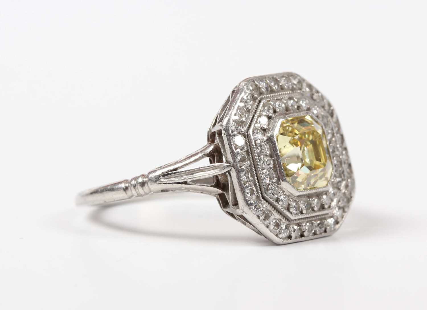 A platinum, fancy intense yellow diamond and diamond ring, mounted with the asscher cut fancy