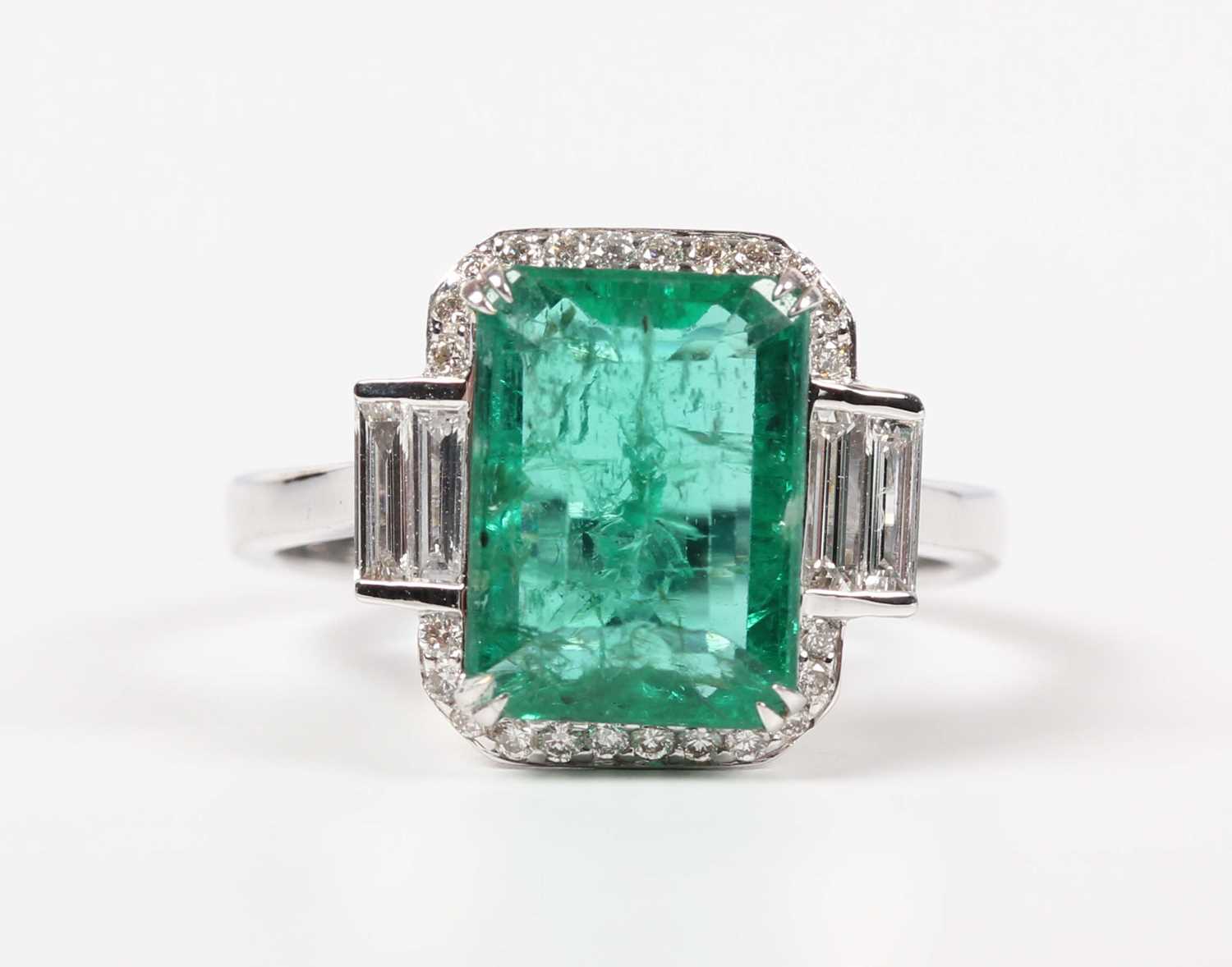 A white gold, treated emerald and diamond ring, claw set with a cut cornered rectangular step cut - Image 2 of 6