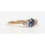 A gold, platinum, sapphire and diamond ring, claw set with a circular cut sapphire between two old