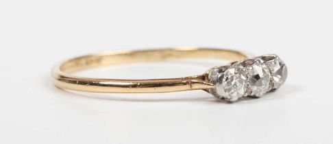 A gold, platinum and diamond three stone ring, claw set with a row of old cut diamonds, detailed ‘