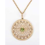 An Edwardian gold, peridot and seed pearl circular pendant of openwork design, mounted with the