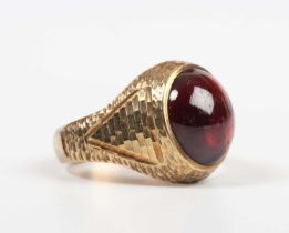 A 9ct gold and carbuncle garnet ring, mounted with an oval carbuncle garnet between textured