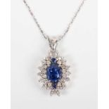 A white gold, sapphire and diamond cluster pendant, claw set with the principal oval cut sapphire