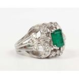 An emerald and diamond cocktail ring, claw set with the rectangular step cut emerald between