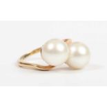 A gold ring, mounted with two cultured pearls in a crossover design, detailed ‘18K’, weight 7.4g,
