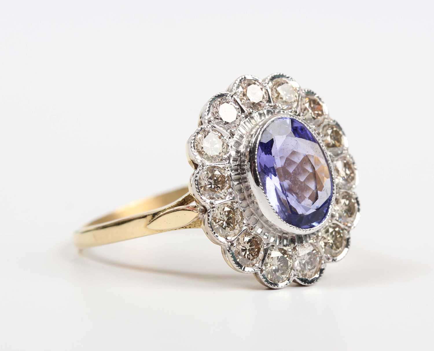 A gold, tanzanite and diamond oval cluster ring, collet set with the oval cut tanzanite within a