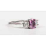 An 18ct white gold, pink sapphire and diamond ring, claw set with the oval cut pink sapphire between