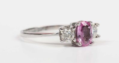 An 18ct white gold, pink sapphire and diamond ring, claw set with the oval cut pink sapphire between