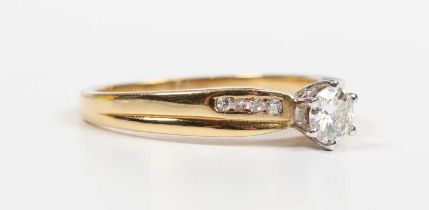 A gold and diamond ring, claw set with the principal circular cut diamond between diamond four stone
