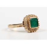 A gold, emerald and diamond cluster ring, collet set with the cut cornered square cut emerald within