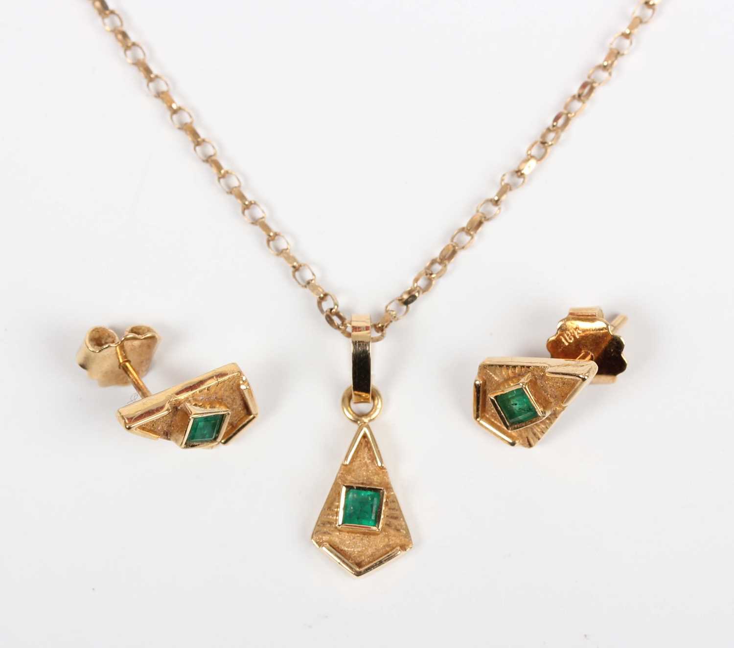 A gold pendant collet set with a cut cornered square step cut emerald to the centre, detailed ‘18K’,