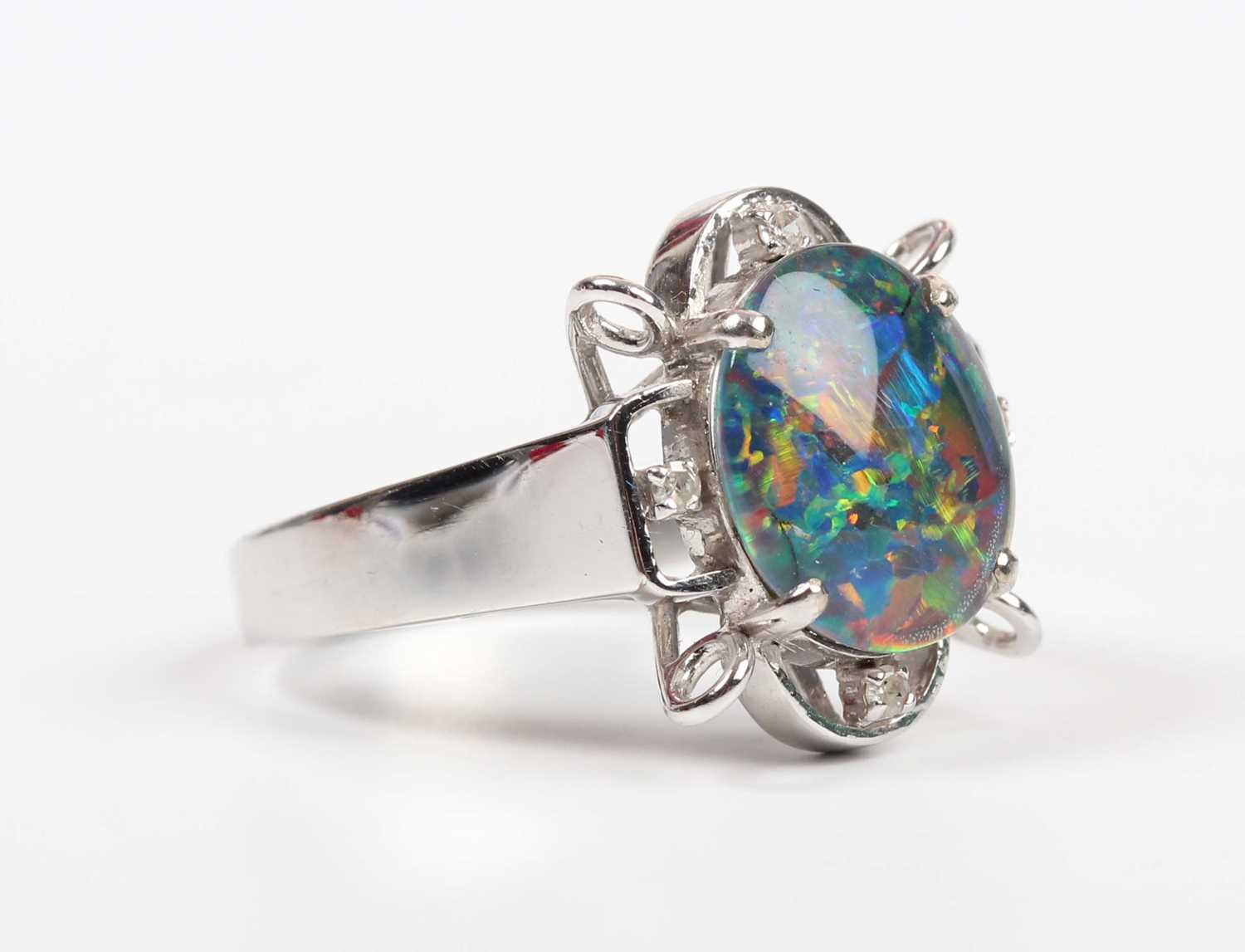 A white gold, opal triplet and diamond ring, claw set with the oval opal triplet in an openwork