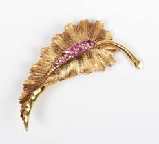 An 18ct gold and ruby brooch, designed as a leaf with a textured finish, mounted with circular cut