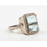 A gold, aquamarine and diamond cluster ring, claw set with the large cut cornered rectangular step