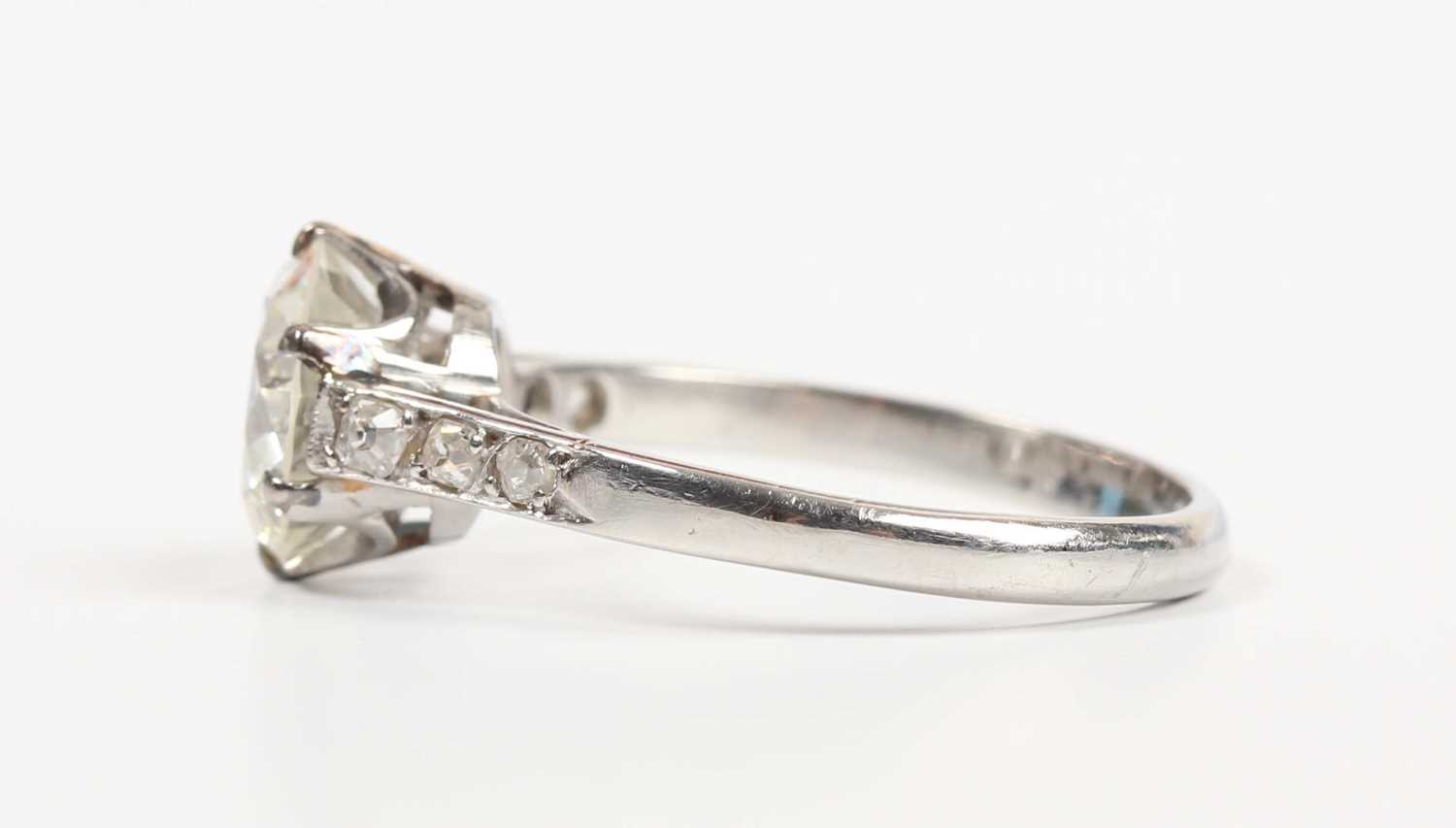 A platinum and diamond ring, claw set with the principal circular cut diamond between diamond - Image 3 of 5