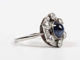 A cabochon sapphire and diamond ring, mounted with the oval cabochon sapphire within an openwork