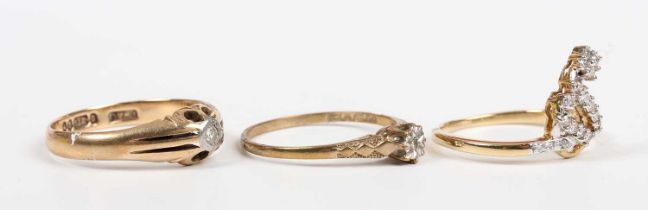 A gold and diamond ring in a scrolling design, mounted with circular cut diamonds, unmarked,