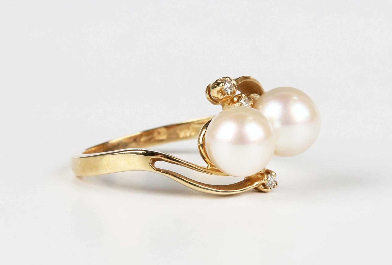 A gold ring, mounted with two cultured pearls and two pairs of circular cut diamonds in a