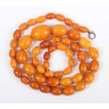 A single row necklace of fifty-one graduated oval opaque and semitranslucent mottled butterscotch