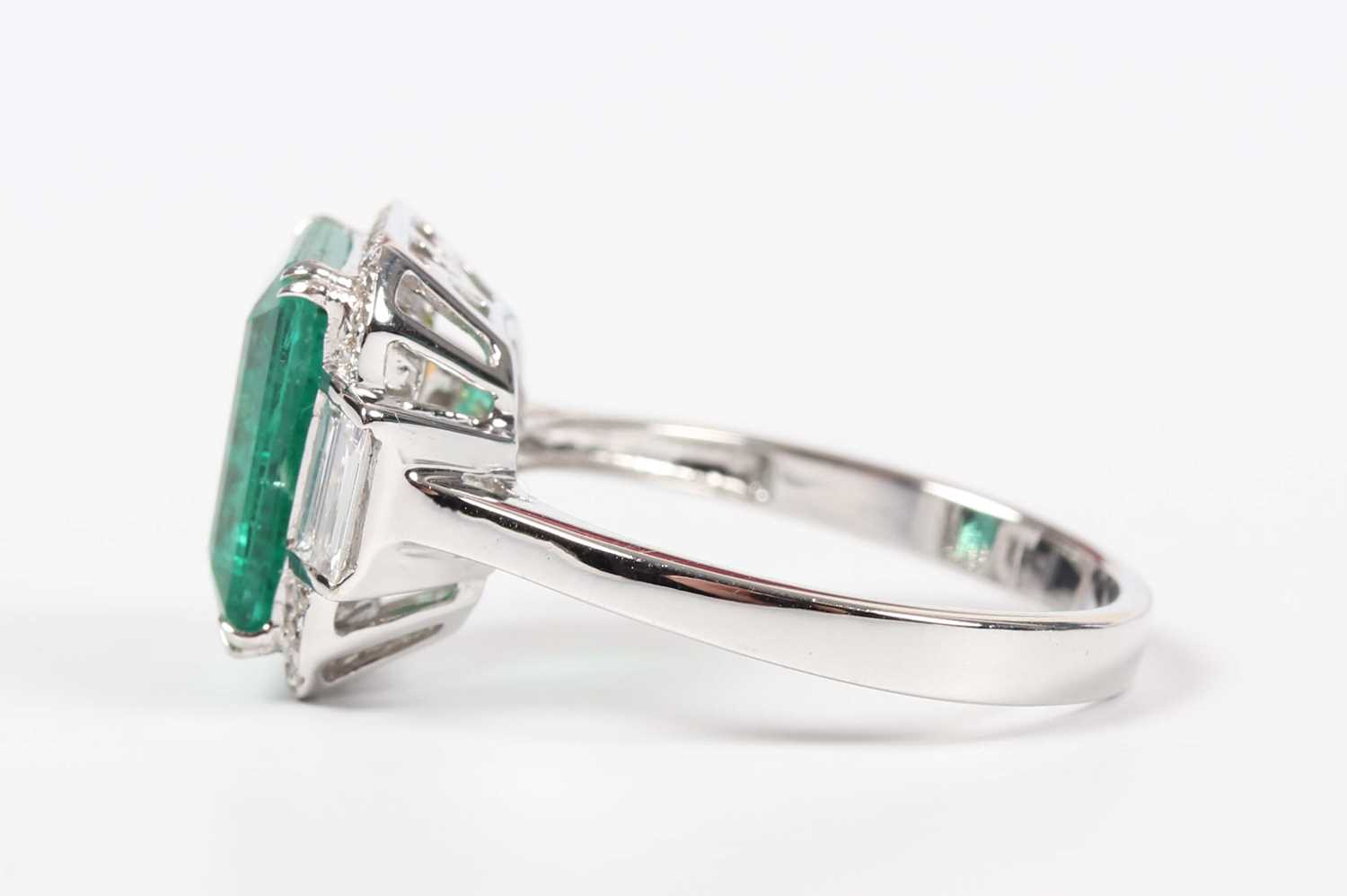 A white gold, treated emerald and diamond ring, claw set with a cut cornered rectangular step cut - Image 3 of 6