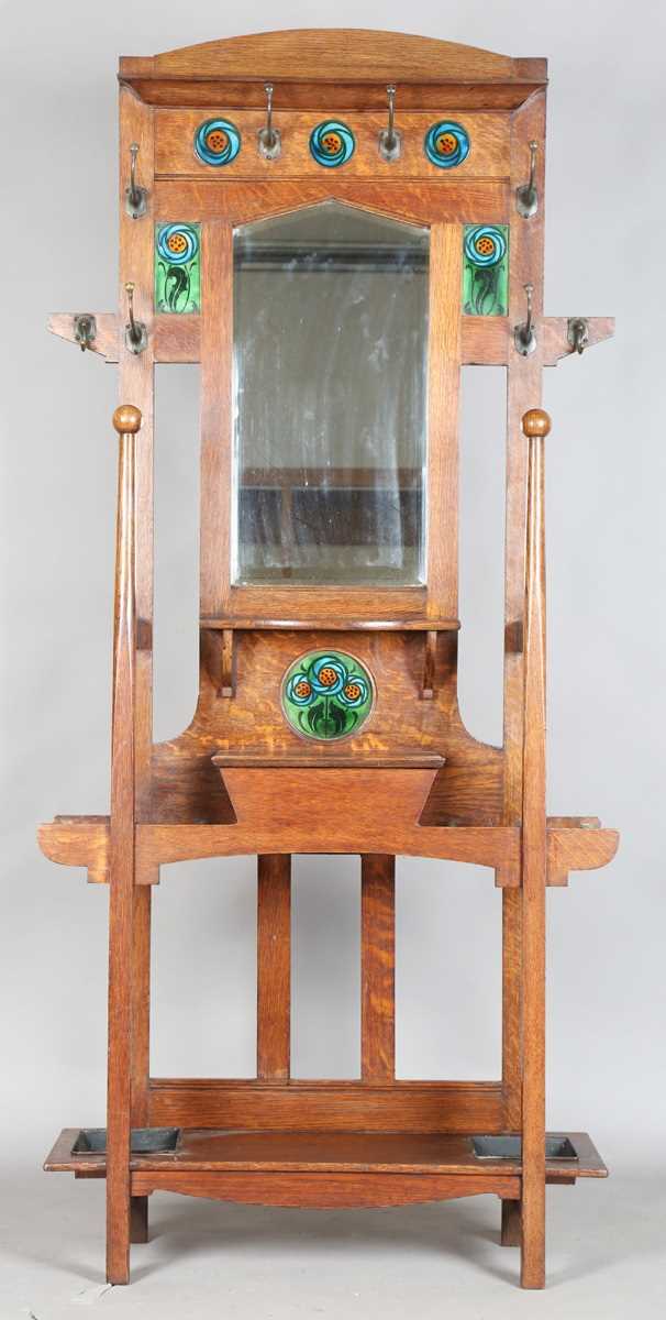 An Edwardian Arts and Crafts Glasgow School oak hallstand, the mirrored back inset with glazed