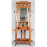 An Edwardian Arts and Crafts Glasgow School oak hallstand, the mirrored back inset with glazed