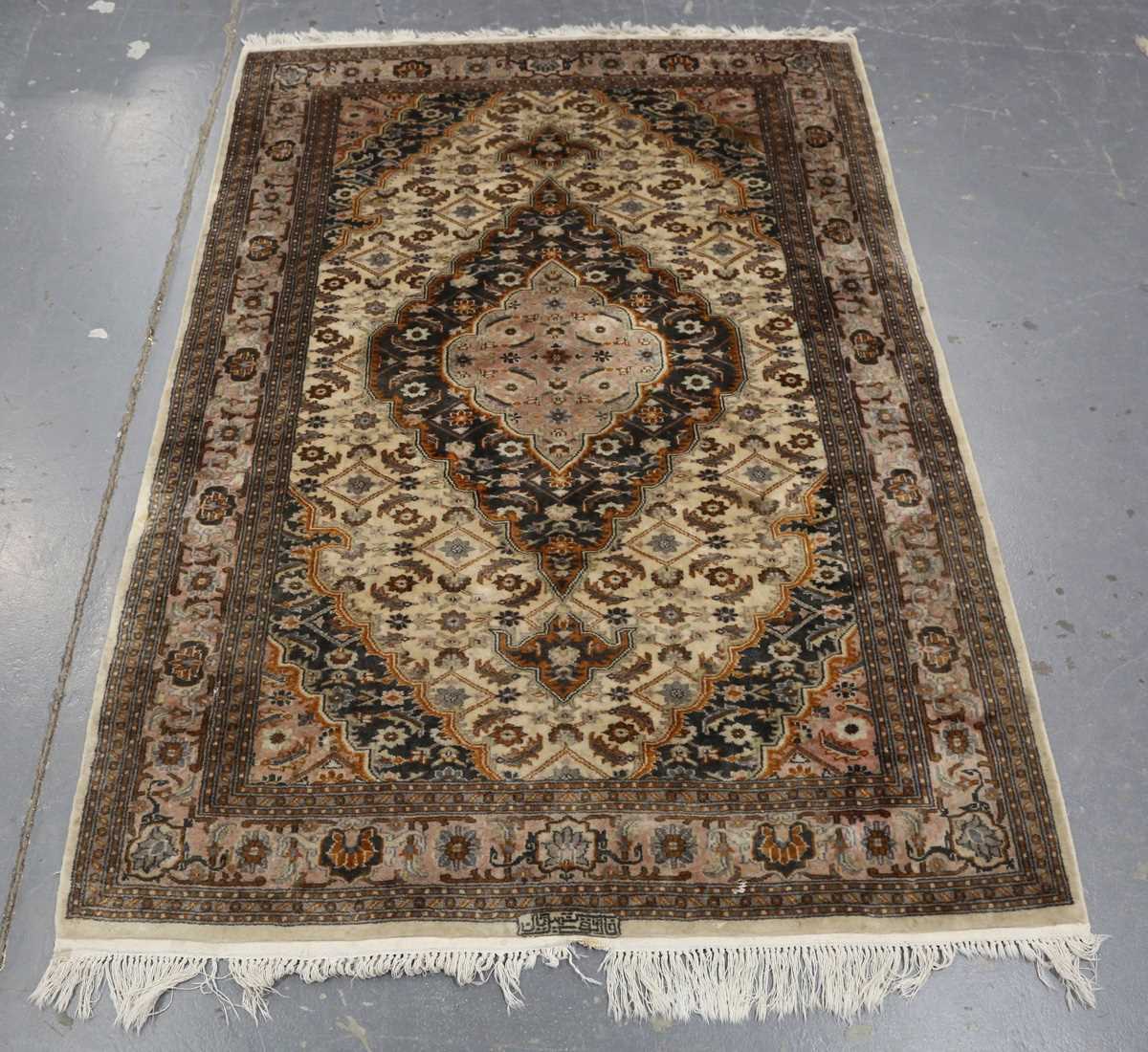 A Kashmir rug, signed, late 20th century, the cream field with a shaped medallion, within a palmette