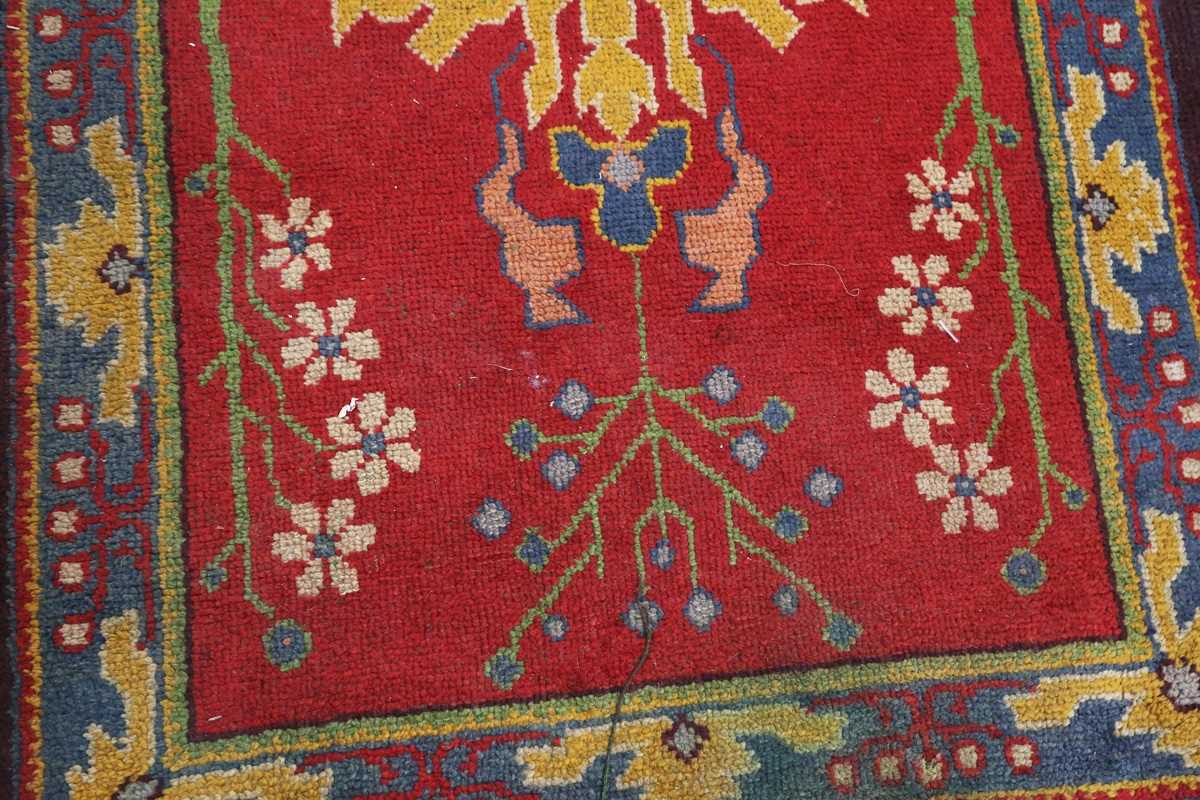 A Donegal Arts and Crafts rug, late 19th century, the red field with bold stylized plants, within - Image 5 of 6