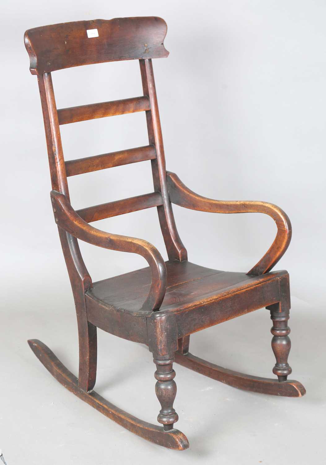 A Victorian provincial mahogany rocking armchair with ladder back and solid seat, height 104cm,