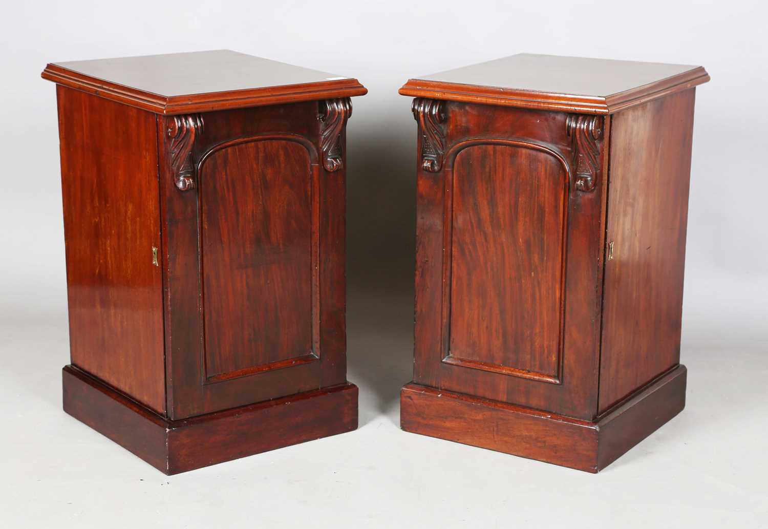 A pair of Victorian and later mahogany pedestal cabinets, each fitted with an arched panel door,