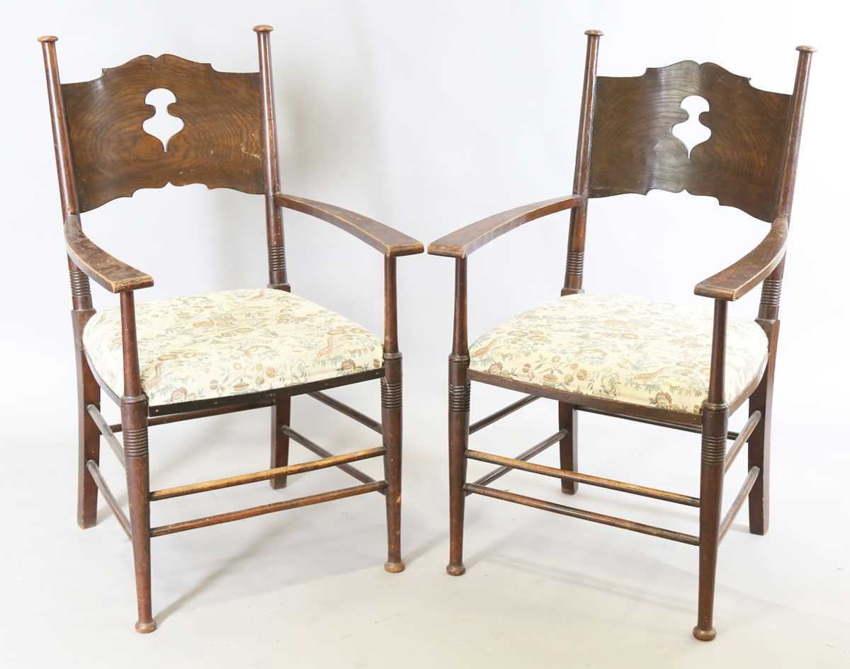 A pair of early 20th century Arts and Crafts oak and ash framed elbow chairs, in the manner of