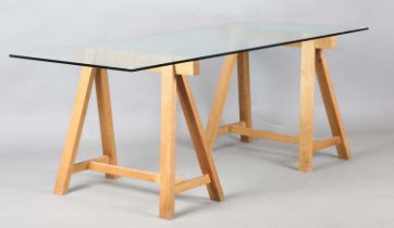 A modern rectangular glass-topped table with a pair of oak trestle supports, height 71cm, length