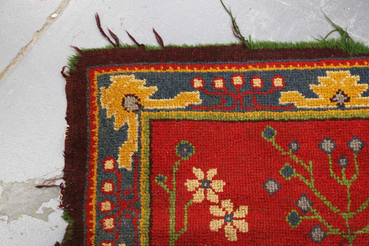 A Donegal Arts and Crafts rug, late 19th century, the red field with bold stylized plants, within - Image 2 of 6