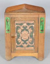 An Edwardian Arts and Crafts oak hanging corner cabinet, possibly by Liberty & Co, the door inset