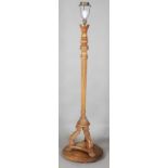 An early 20th century Baroque Revival walnut lamp standard with a fluted stem and triform base,