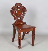 A mid-Victorian mahogany hall chair, the finely carved shield back above a solid seat, raised on