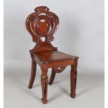 A mid-Victorian mahogany hall chair, the finely carved shield back above a solid seat, raised on