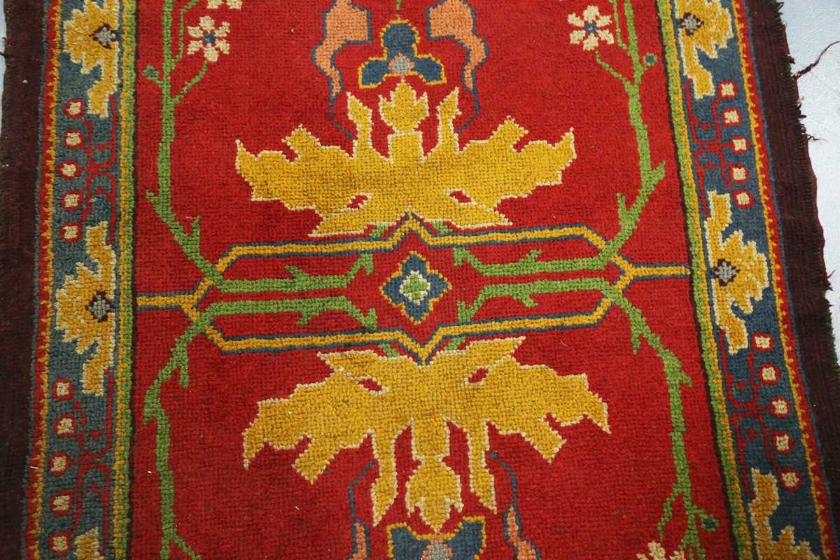 A Donegal Arts and Crafts rug, late 19th century, the red field with bold stylized plants, within - Image 4 of 6