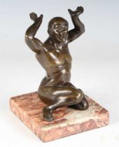 An early 20th century Continental brown patinated cast bronze figure of a kneeling nude male, raised